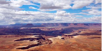 Expansive desert canyon landscape under partly cloudy sky.
