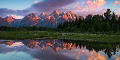 Majestic mountain range reflected in a tranquil lake at sunset.