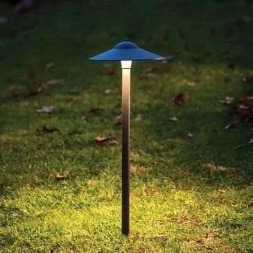 A modern garden lamp illuminating grass at night.