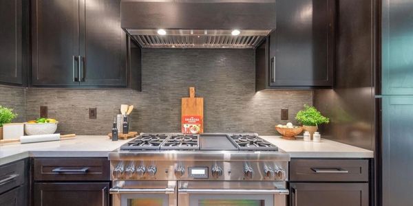 Modern kitchen with stainless steel stove and dark cabinetry.