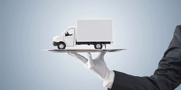 A small delivery truck on a silver platter held by a gloved hand.
