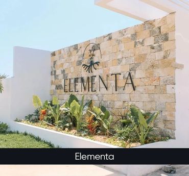 Stone wall with 'Elementa' sign and lush greenery in front.