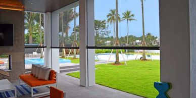 Modern patio with orange seating overlooking a lush green lawn and pool.