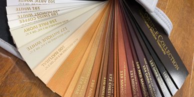 A fan of wood stain color samples arranged on a wooden surface.