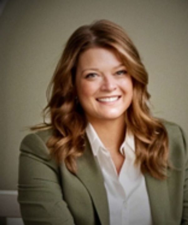 Smiling woman with wavy hair in a green blazer and white shirt.