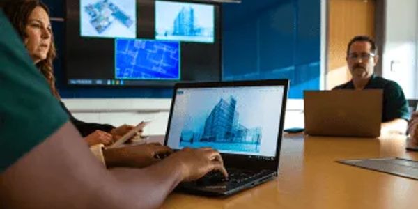 People discussing architectural designs on laptops and screen.