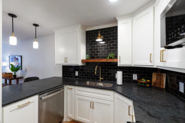 Modern kitchen with white cabinets and black subway tile backsplash.