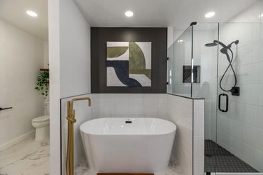 Modern bathroom with freestanding tub, glass shower, and abstract wall art.