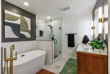 Modern bathroom with freestanding tub, glass shower, and wooden vanity.
