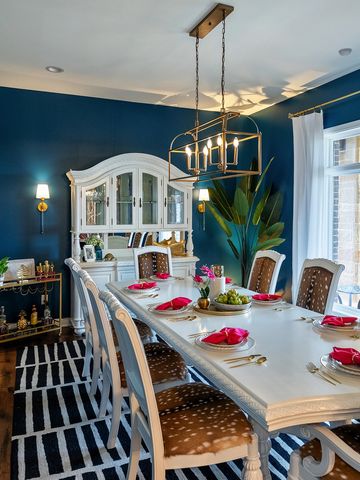 Elegant white dining set with navy walls and stylish chandelier.