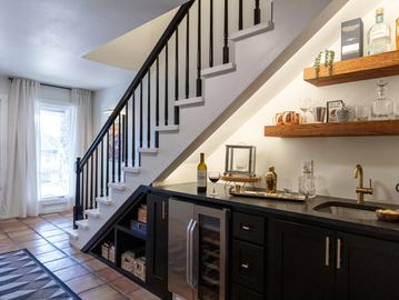 Modern under-stair bar area with wine cooler and floating shelves.
