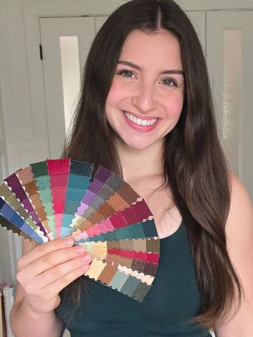 Smiling woman holding a colorful fabric swatch fan.