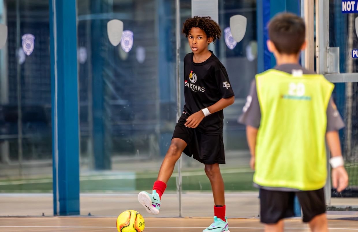 Two boys playing indoor soccer, one preparing to kick the ball.