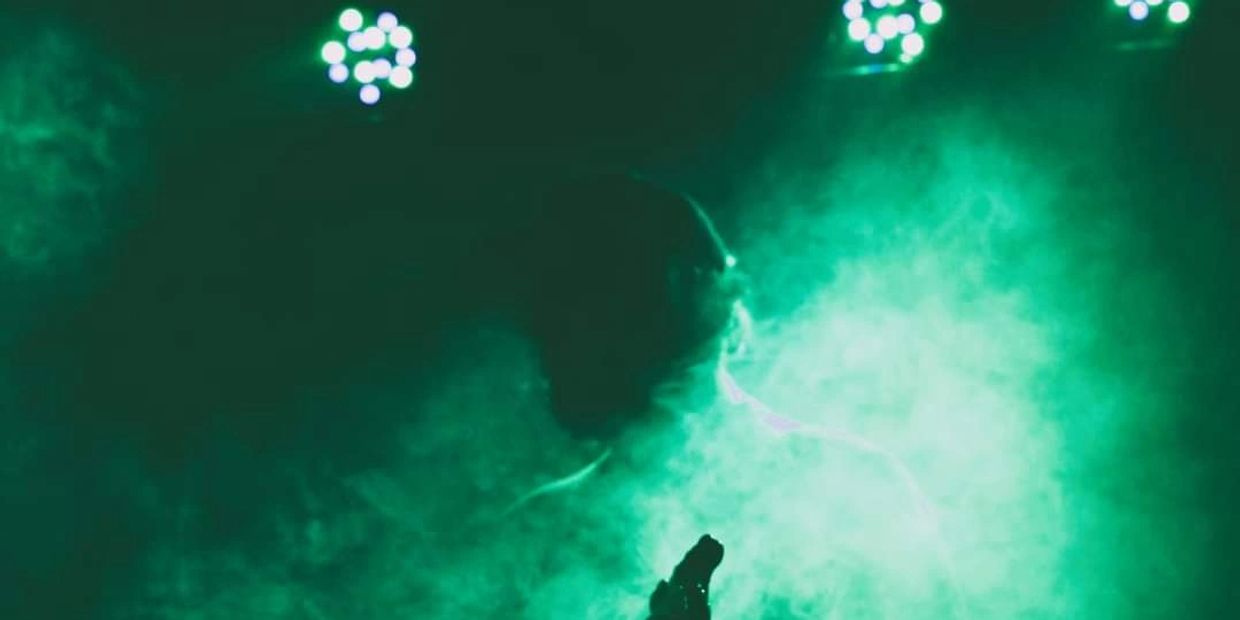 Stamati Dendis playing bass onstage engulfed in green smoke
