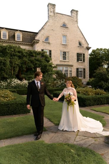 Newlywed couple walking hand in hand outdoors.