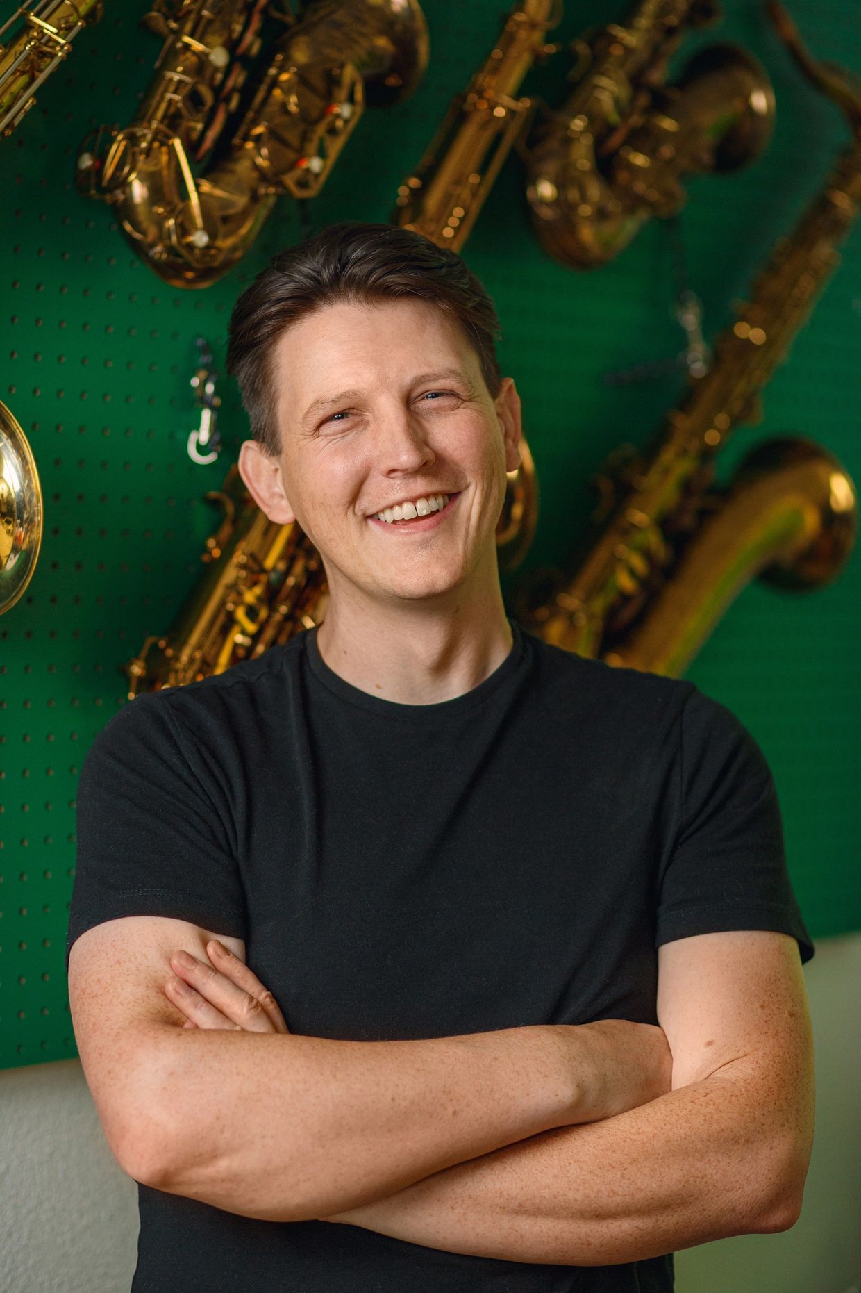 Man smiling with saxophones in the background.