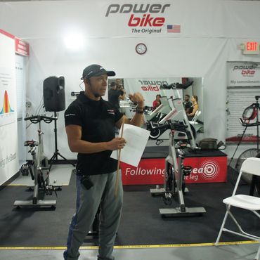 Instructor explaining Power Bike workout techniques in a fitness studio.