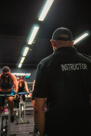 Instructor overseeing a group indoor cycling class in a gym.