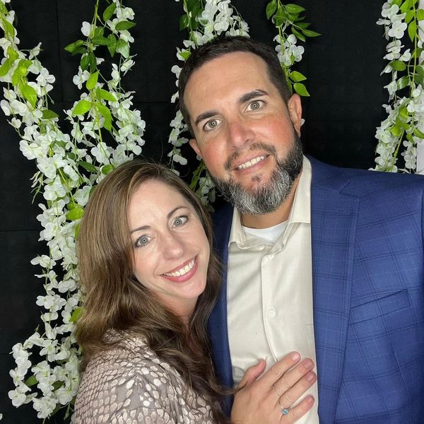 Smiling couple posing in front of a floral backdrop.