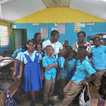 Group of smiling schoolchildren and teachers in a colorful classroom.