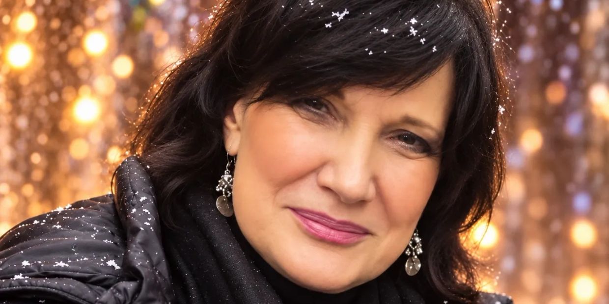 Woman smiling with snowflakes on her hair and jacket.