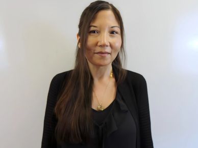 Woman with long hair smiling gently against a plain background.