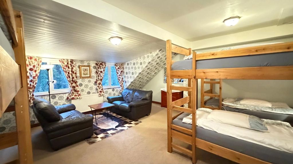 Spacious family room with bunk beds and a seating area, sleeps up to 6 people. Forest Views.