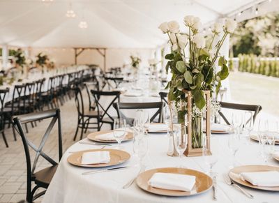 Black cross back chairs at round table with wood lantern and roses.