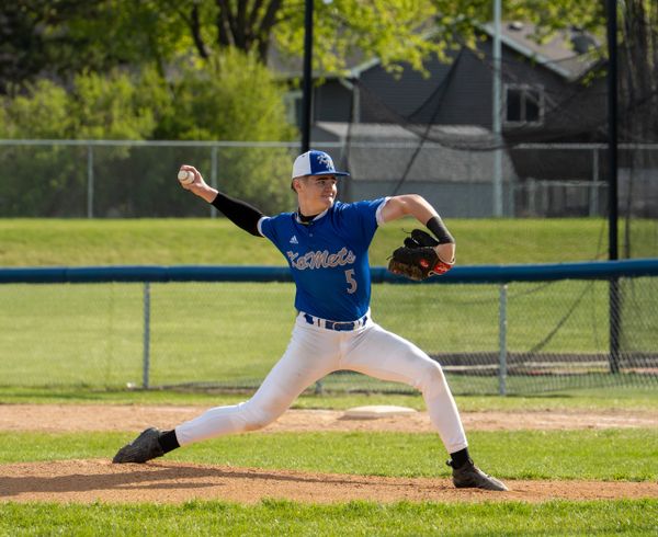 Baseball pitcher in blue uniform mid-throw on the mound.