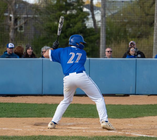 Baseball player in blue jersey preparing to bat during a game.