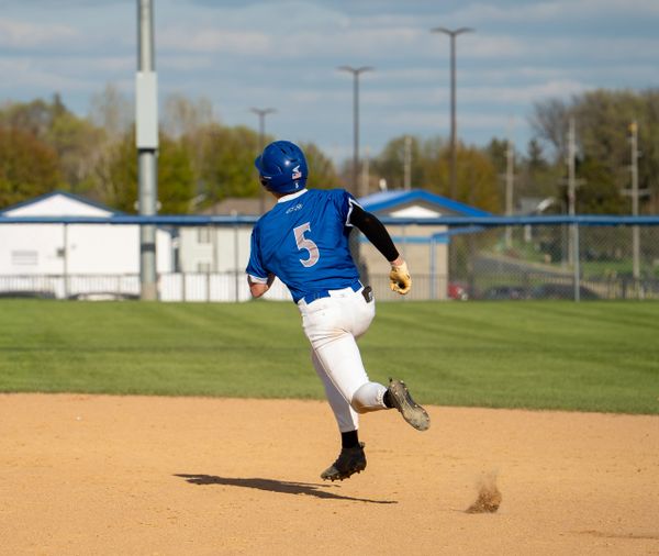Baseball player in blue jersey running on the field.