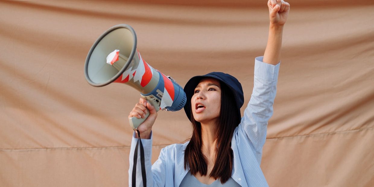 Woman holding a megaphone and raising her fist.