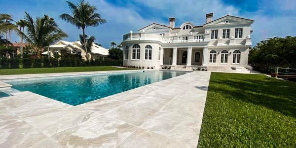 Luxurious white mansion with a pool and palm trees.
