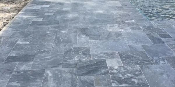Gray stone tiled pathway near water.