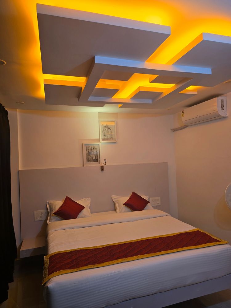 “Elegant hotel bedroom with double bed, soft lighting, modern false ceiling design, and comfortable”