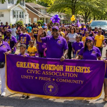 Community members march with a banner for Greater Gordon Heights Civic Association.