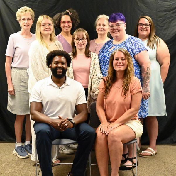 Group portrait of ten smiling people with diverse appearances.