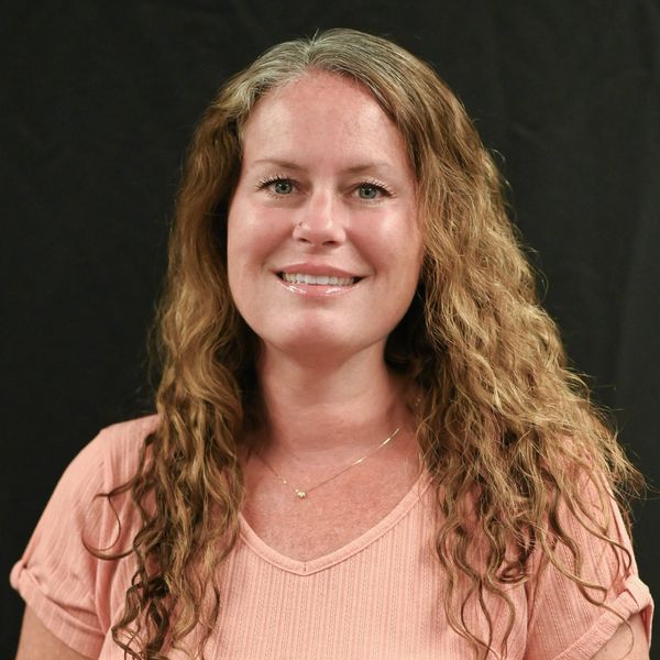 Woman with long curly hair smiling at the camera.