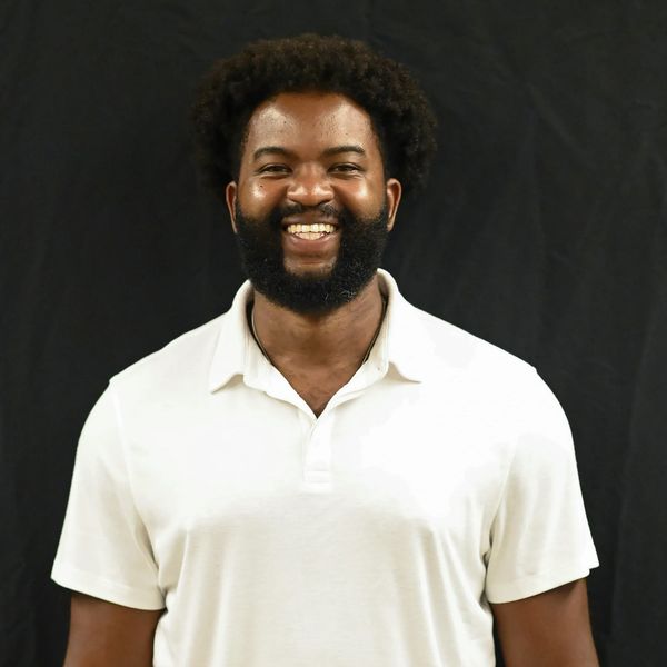 Smiling man with beard wearing white polo shirt.