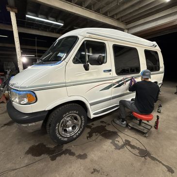 Person detailing a white van inside a garage.