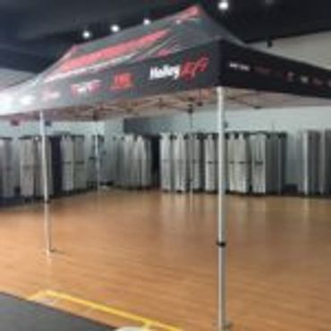 A branded canopy tent set up indoors on a wooden floor.