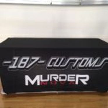 Black tablecloth with white and red text advertising 187 Customs Murder Indoor.