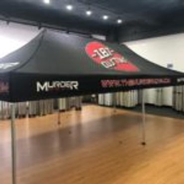Black tent with Murder Mystery branding set up indoors.