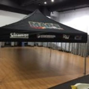 Black promotional tent with logos set indoors on wooden floor.