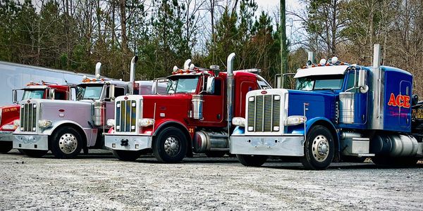This photo shows three heavy wrecker tow trucks in silver, red, and blue.