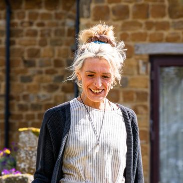 Smiling woman with blonde hair in a casual outfit outdoors.