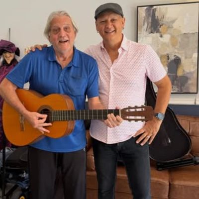 Two men posing with a guitar indoors.