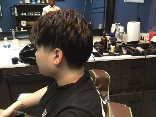 A person sits in a barber's chair with a stylish, cropped hairstyle