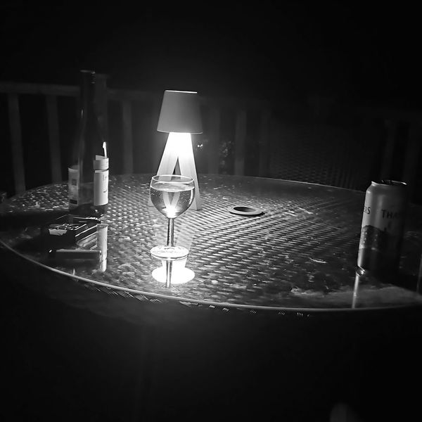 Riverside glamping pod deck near Builth Wells, Powys Wales with drinks by lamplight at night.