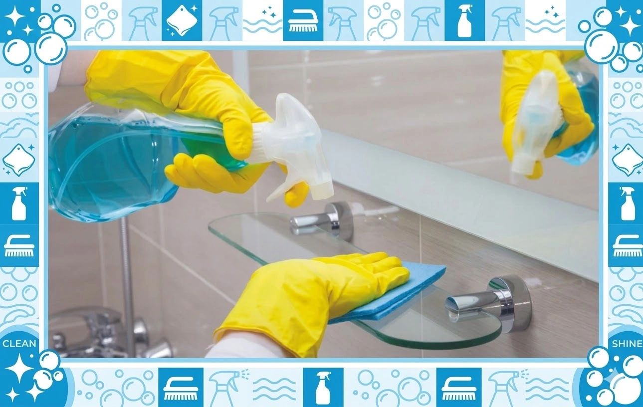 Person cleaning a glass shelf with spray and cloth wearing yellow gloves.